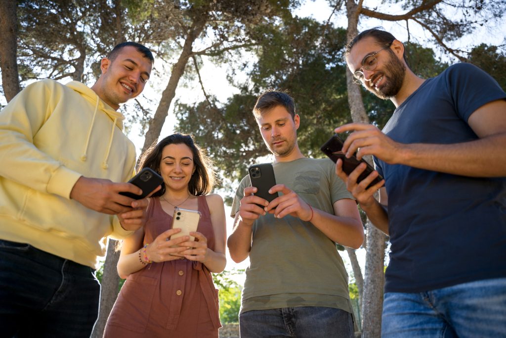 Group of friends smiling while using the mobile phone