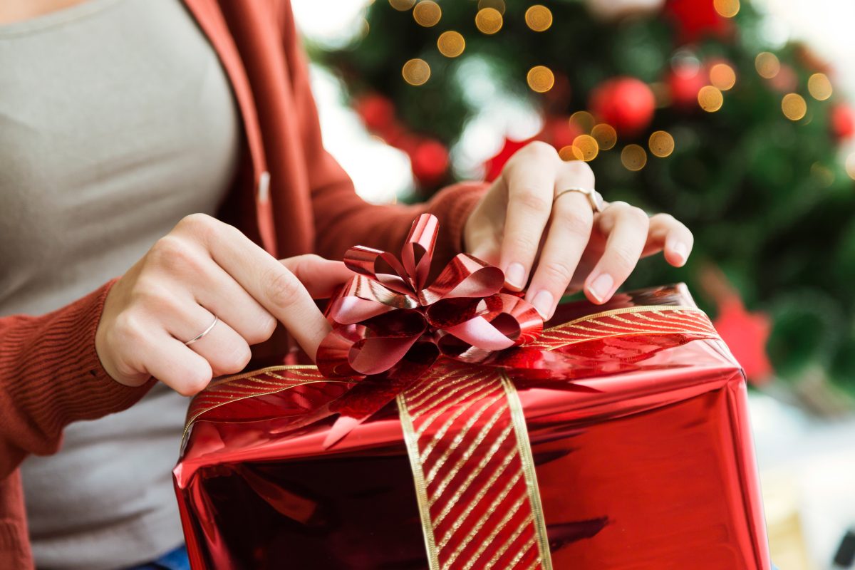 Beautiful young woman opening presents on Christmas day.